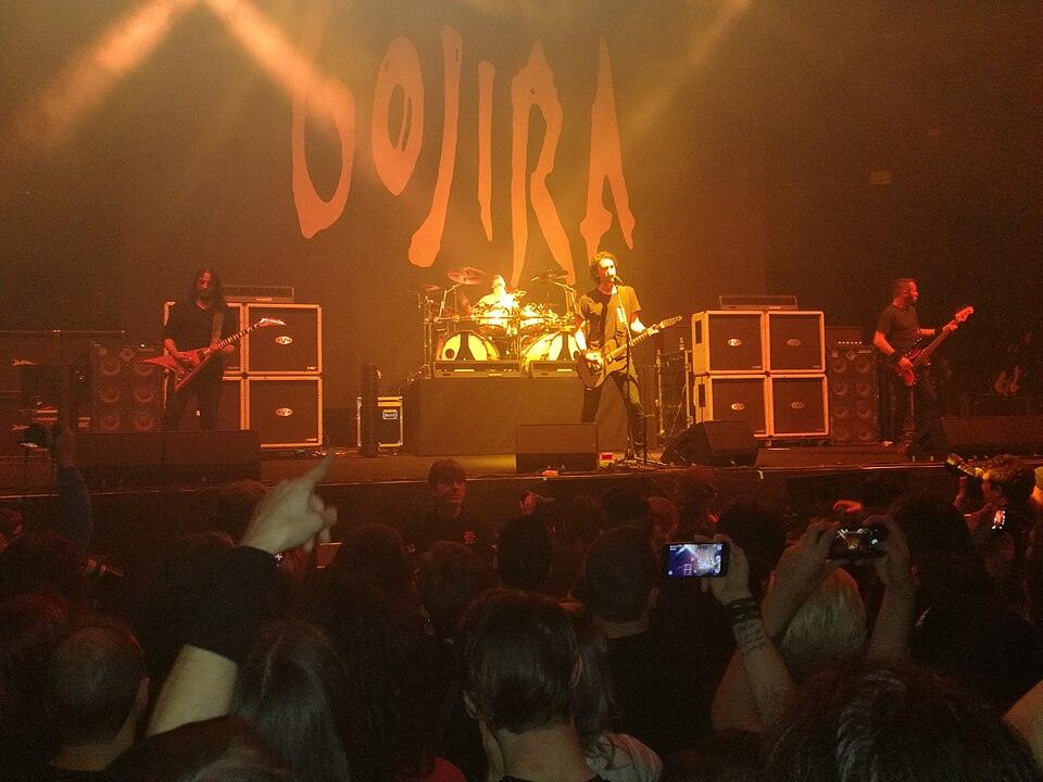 Groupe gojira sur scène avec des lumières rouges haut et un public devant la scène