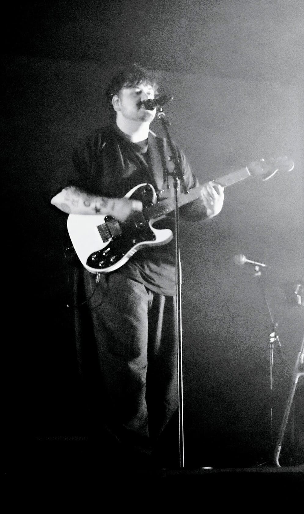 Portrait en noir et blanc de l'artiste Stgraal, les yeux fermés, chantant sur scène devant son micro.