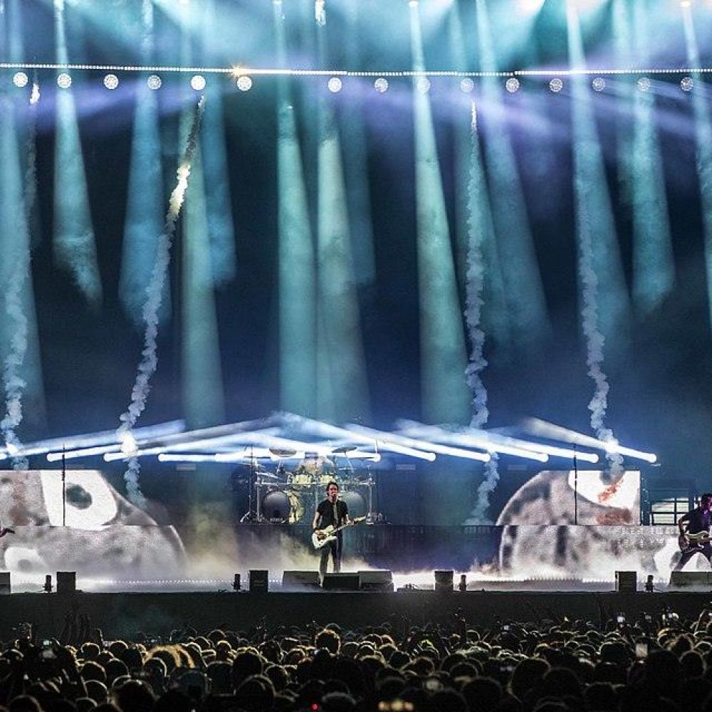 Groupe gojira sur scène au Helfest avec des lumières bleus en fond et un public devant la scène